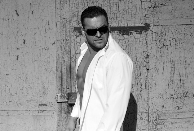 Confident macho male man brutal urban style attractive bristle guy in white shirt and sunglasses