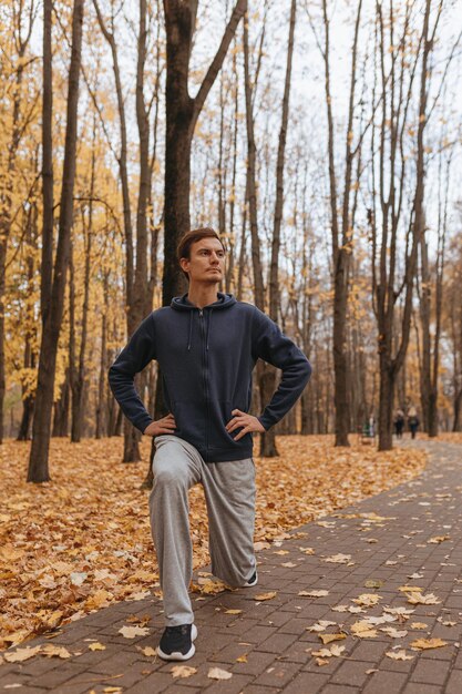 confident male athlete doing lunge exercise and stretching legs in park