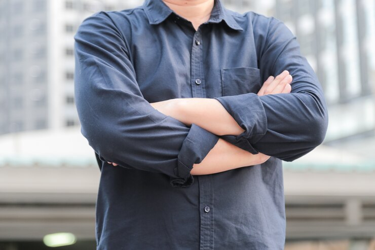 Photo オフィスビルの前に立つ腕を持つ自信のある男性ビジネスエグゼクティブ