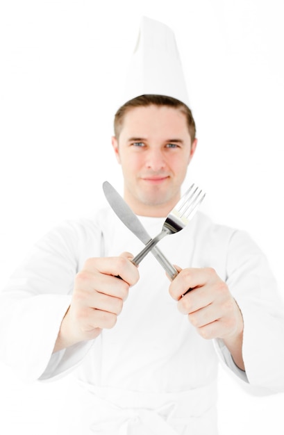 Confident male cook holding fork and knife smiling at the camera