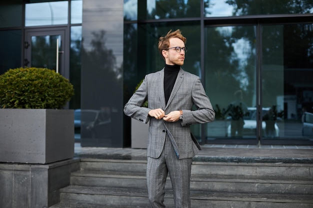 Confident male entrepreneur buttons up his formal suit jacket outside the corporate office building