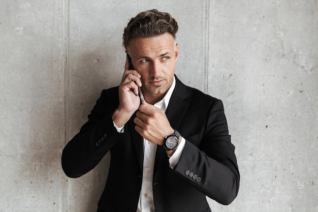 Confident man dressed in suit talking on mobile phone