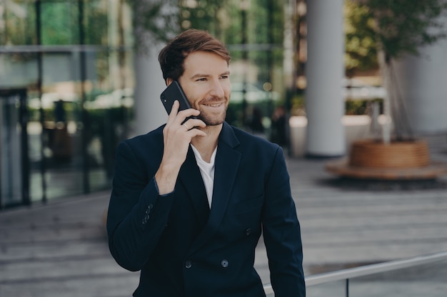 Confident man entrepreneur dressed in formal clothes makes phone call in roaming