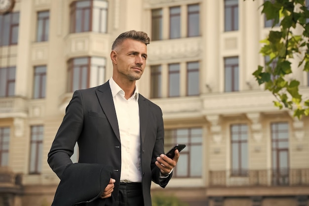 Confident man formal outfit modern life concept businessman on way to office agile business use phone while walking urban style and everyday life ordinary working day charismatic man in suit