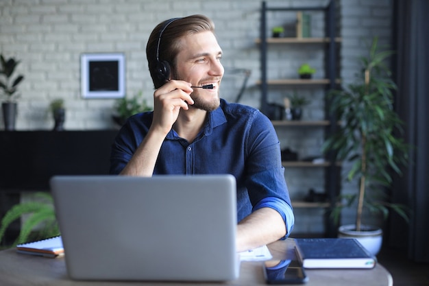 Confident man wearing headset speaking and watching business webinar training, listening to lecture.