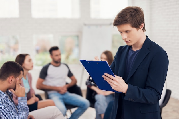 Confident man with blue tablet at group support meeting