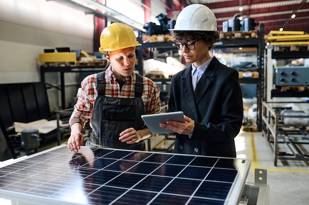 Confident manager with tablet showing young female engineer online data