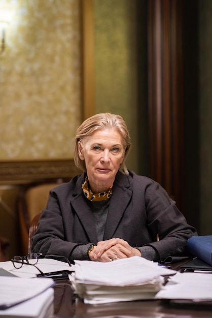 confident mature female lawyer looking at you while sitting by workplace