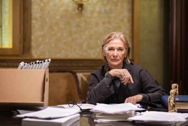 confident mature female professional sitting by workplace