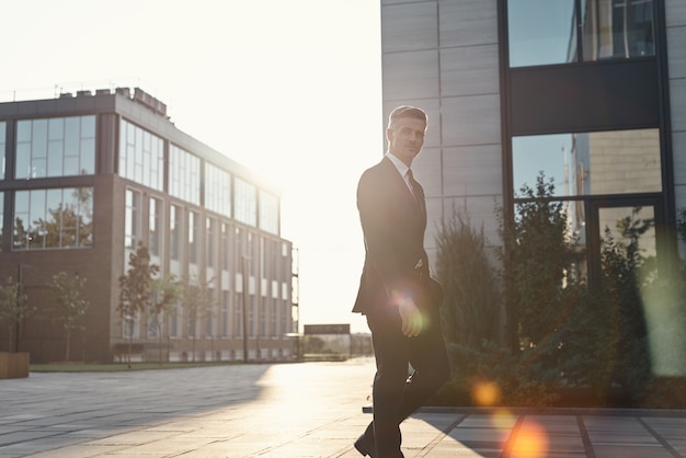 Confident mature man in full suit walking near office buildings outdoors