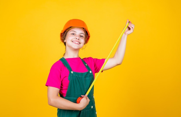 Meccanico fiducioso. futuro ingegnere. il bambino felice usa lo strumento di riparazione del metro a nastro. cantiere edile. bambino architetto lavoratore. concetto di festa del lavoro. sviluppo dell'infanzia. assistente ragazza adolescente.