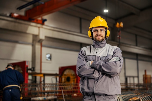 A confident metallurgy worker in protective work wear is standing in facility