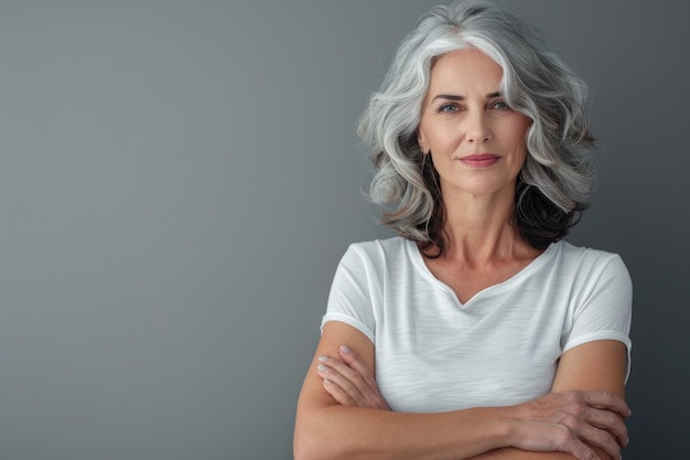 Foto donna di mezza età sicura con le braccia incrociate su uno sfondo grigio