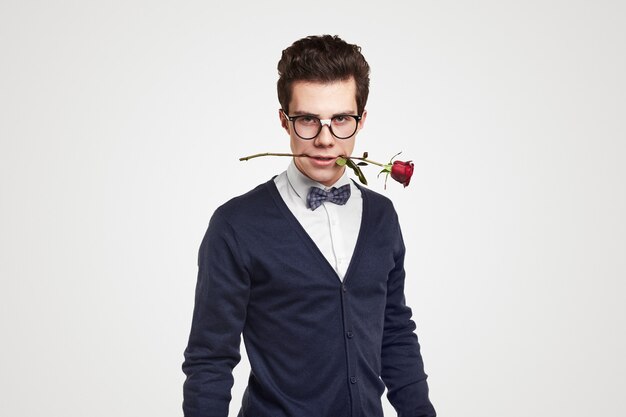 Confident nerdy man with rose in mouth