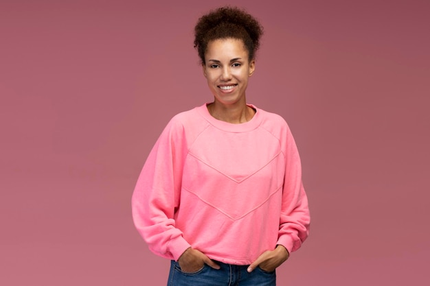 Confident portrait stylish smiling young multiethnic woman with afro hair isolated pink background