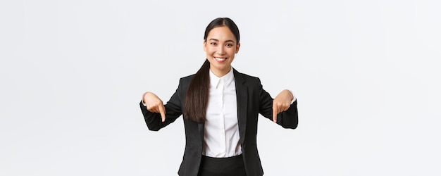 Confident professional saleswoman suggest good deal best prices Smiling goodlooking female real estate agent showing bottom advertisemenet Businesswoman in suit pointing fingers down