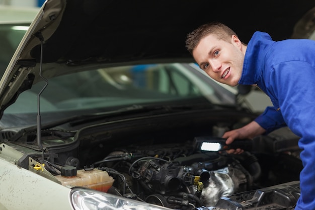 Confident repairman examining car engine