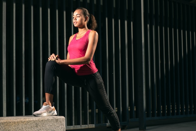 Confident runner stretching muscles and warming up with one foot on the stone