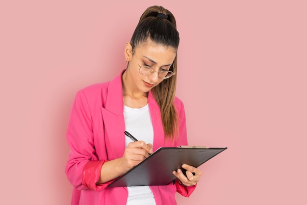 Confident serious brunette caucasian business employee woman holding clipboard and pen taking notes