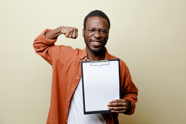 Confident showing strong gesture young african american male holding clipboard isolated on white background