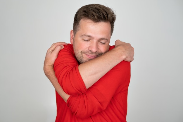 Foto uomo caucasico sorridente sicuro che tiene abbracciandosi