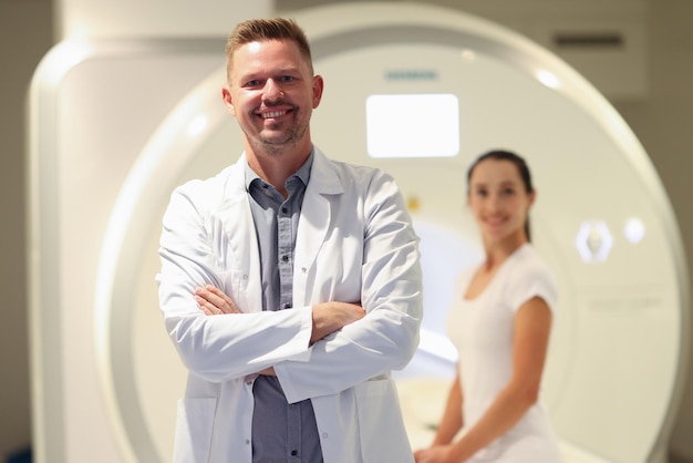 Confident smiling male doctor closeup and female patient and ct scanner in background mri scan