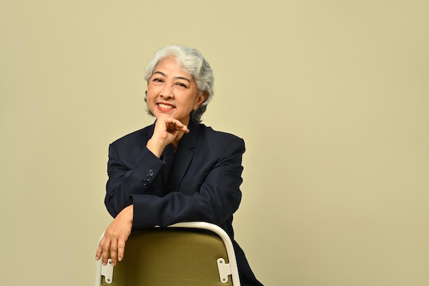 Confident smiling mature businesswoman in formal attire isolated in beige background