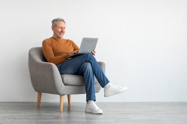 Confident smiling mature man using laptop at home