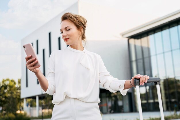 Confident smiling middle aged businesswoman holding mobile phone, checking email on the street