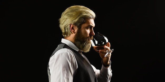 Confident sommelier Male skilled sommelier estimates alcoholic drink red wine in wineglasses bearded