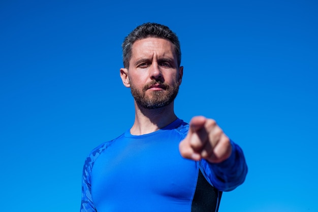 Confident sportsman in sportswear pointing finger on sky background fitness trainer