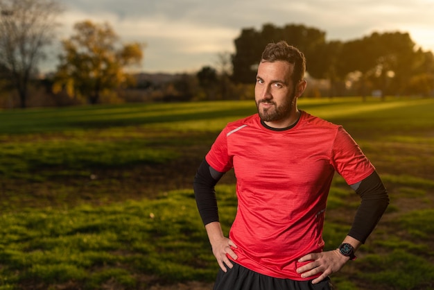 Confident sportsman standing with hands on waist in park