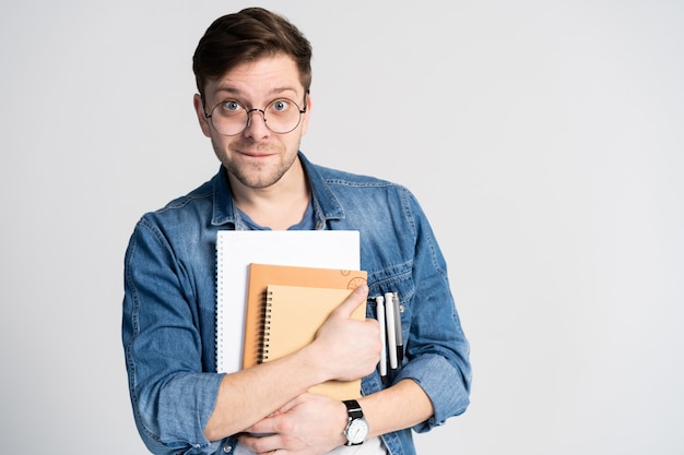 Confident student. portrait of handsome young man holding books. Isolated on white.