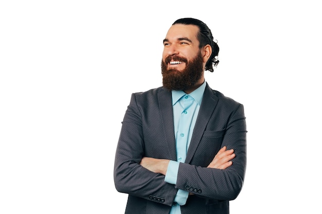 Confident studio portrait of a bearded man wearing jacket with crossed arms