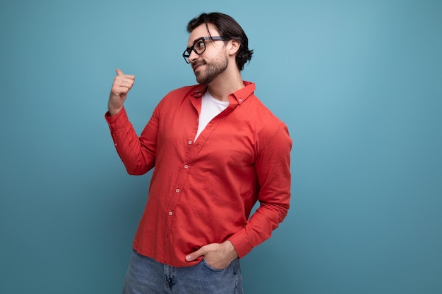 confident stylish 35 year old brunette millennial man with gorgeous hair in a red shirt on a studio background with copy space