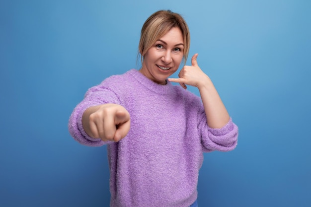 Confident stylish blond young woman in a casual look with a good mood holds out her hand on a bright