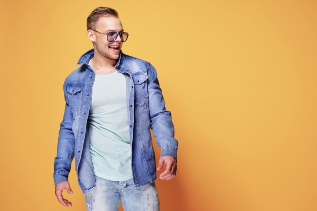 Confident stylish casual guy posing on yellow