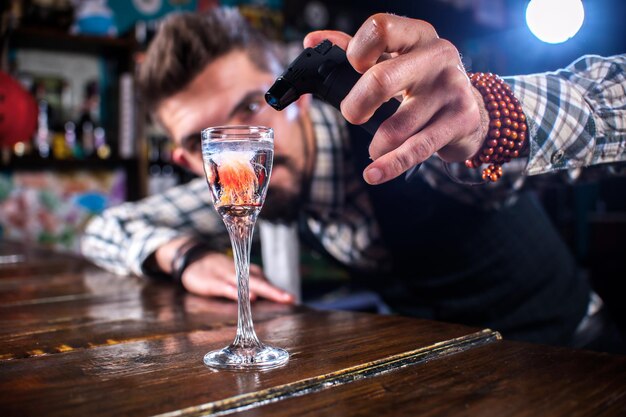 Confident tapster decorates colorful concoction while standing near the bar counter in pub