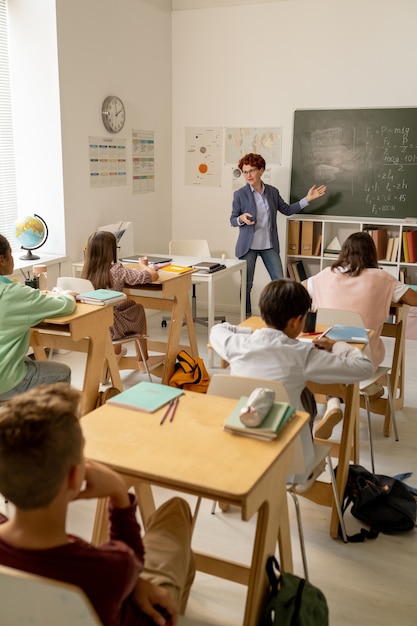 칠판으로 학생들에게 새로운 공식을 설명하는 자신감 있는 교사