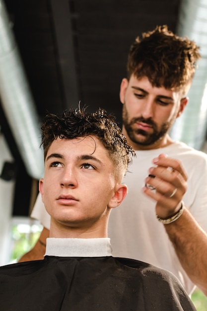 Confident teenager visiting hairstylist in barber shop