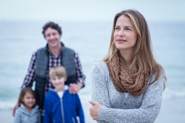 Confident woman standing against family at beach 