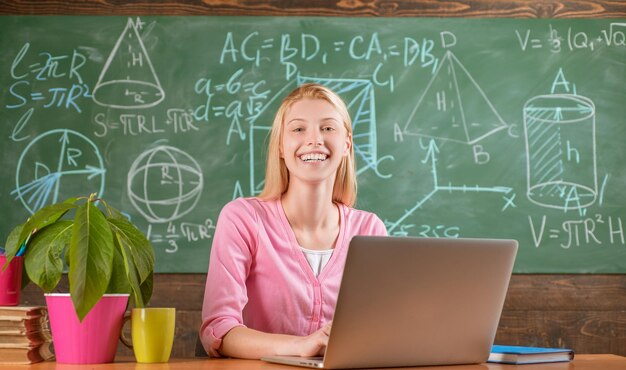 Confident woman with laptop working online teacher. Modern education. Back to school. Remote education. Student adorable blonde girl classroom chalkboard background. STEM concept. Formal education