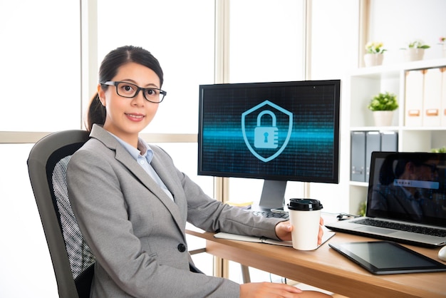 사이버 보안 회사에서 일하는 자신감 넘치는 여성, 사무실에 앉아 커피 한 잔을 들고 휴식을 취하고 있습니다