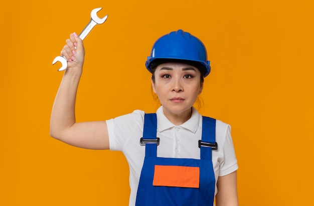 Confident young asian builder girl with blue safety helmet holding workshop key 