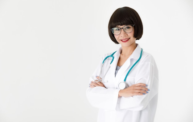 Confident young Asian female medic in glasses with stethoscope looking at camera friendly against white background