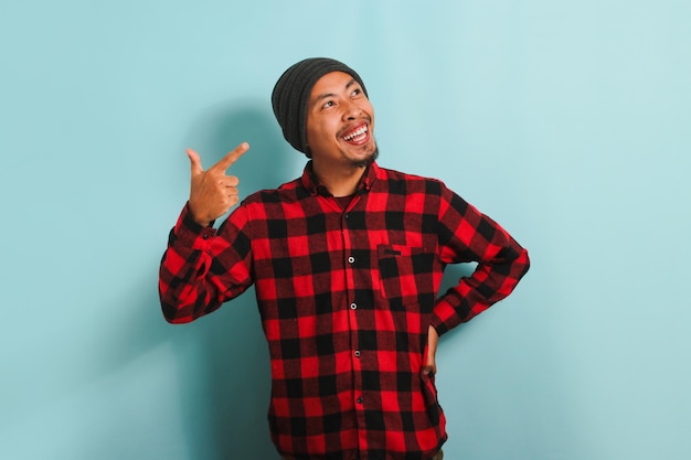 Confident young Asian man is pointing his finger to the right copy space isolated on blue background