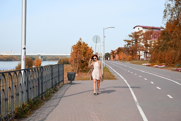 A confident young attractive woman in a coat and highheeled shoes walks through the streets of the