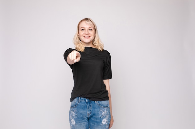 Confident young beautiful woman showing by hand ooking at camera posing isolated