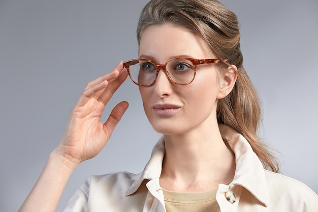 Confident young business woman 35-45 years old, blonde stilish formal clothes and glasses, gray background, close-up. Business and career success concept.