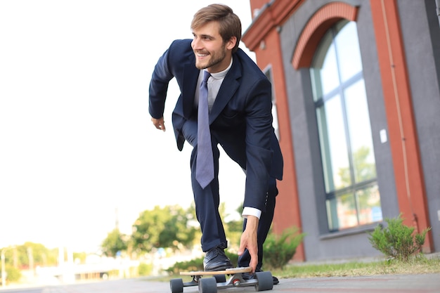 Confident young businessman in business suit on longboard hurrying to his office, on the street in the city.